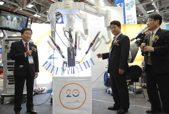 로봇수술 전문회사 인튜이티브서지컬코리아는 지난 24일부터 26일까지 대구 엑스코에서 개최된 '2016 메디엑스포'에서 '다빈치 Xi 로봇수술기'를 비롯한 최첨단 의료기술을 선보여 의료진 및 관람객들의 주목을 받았다고 밝혔다. 이번 전시회에 선보인 다빈치 Xi 시스템은 인튜이티브서지컬 코리아의 최신 로봇수술기 모델로, 고화질 3D 화면과 손목기능이 있는 소형 수술 기구를 이용하여 의료진들이 정교한 방법으로 최소침습수술을 할 수 있게 도와준다. 이번 전시 기간 동안 인튜이티브서지컬 코리아의 부스를 방문한 관람객들은 약 1만명에 이른다. 사진은 개막식에서 차순도 대구의료관광진흥원장(왼쪽부터),권영진 대구시장이 로봇으로 리본을 컷팅하는 모습.      인튜이티브서지컬 코리아 제공